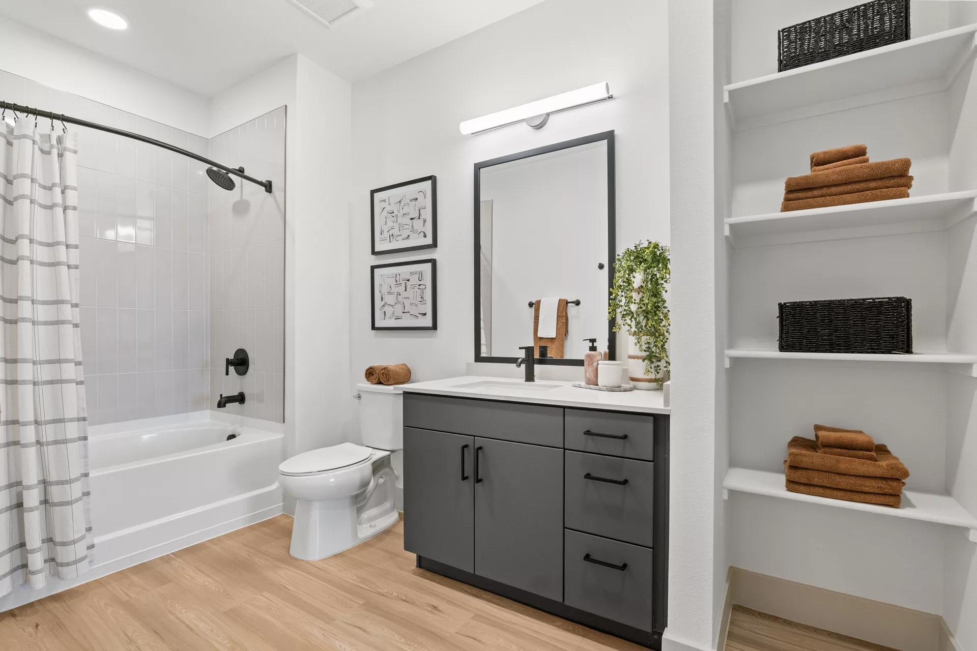 Bathroom with gray vanity, white quartz countertop, and open shelving with towels.