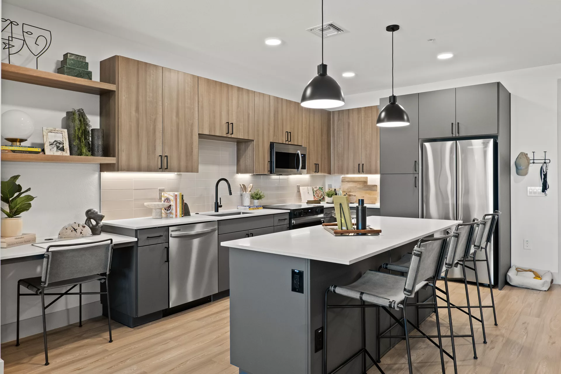 Modern kitchen with gray cabinets, wood accents, white countertops, island with seating, and...