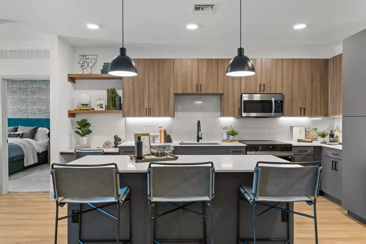 Modern kitchen with island, white countertops, wood and gray cabinets, and pendant lighting.