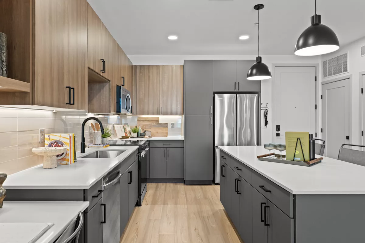 Modern kitchen with gray cabinets, white countertops, stainless steel refrigerator, and...