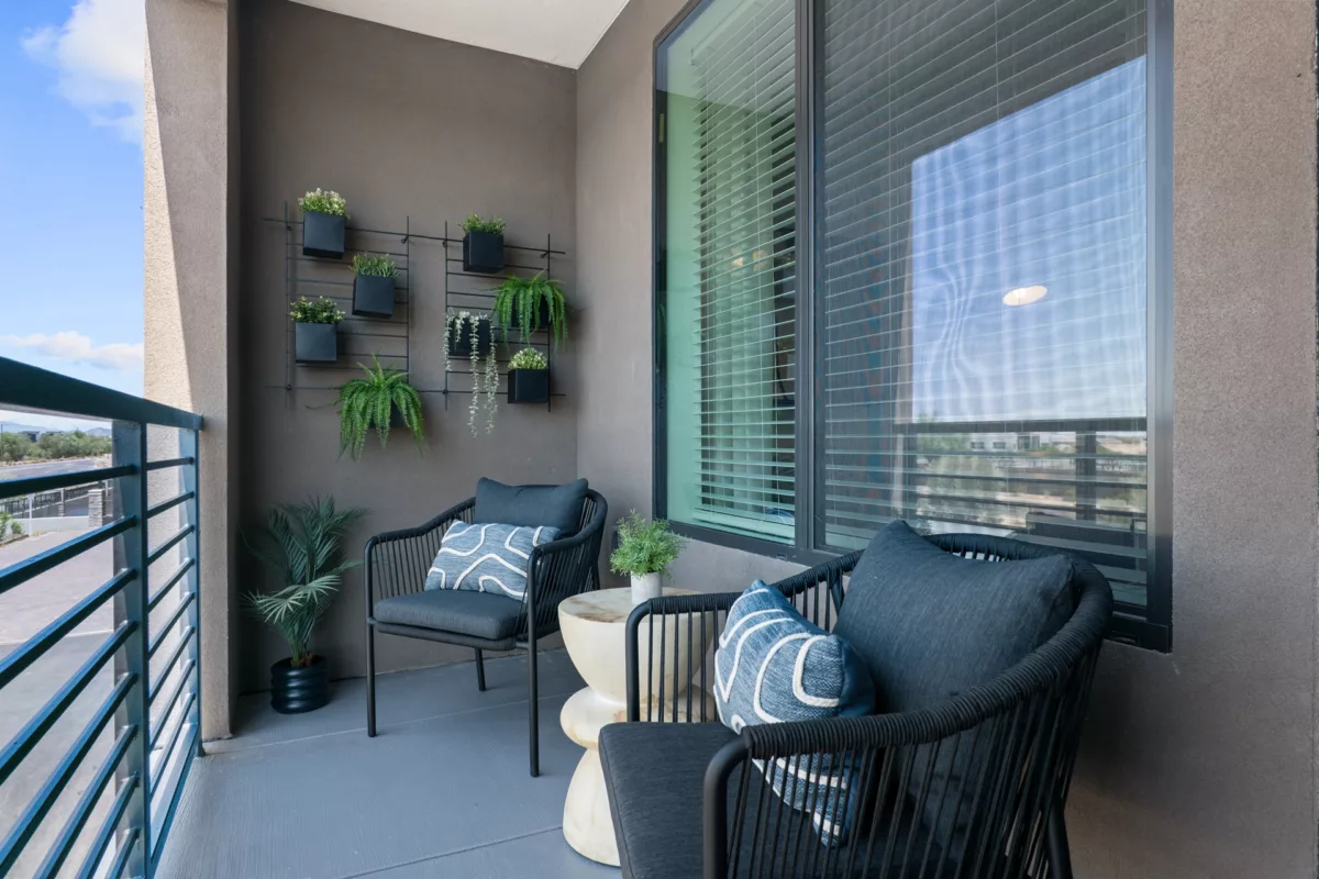 Balcony with two chairs, side table, wall planters, and view through railing.