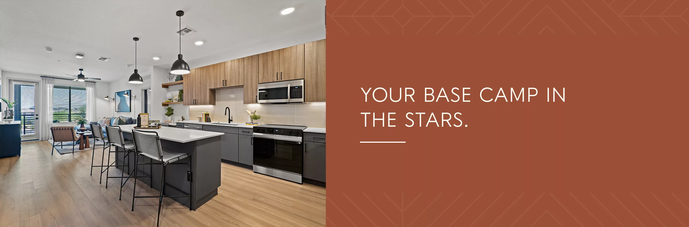 A photo of a kitchen with an island and gray and light wood cabinets, to the left of the tagline "Your Base Camp in the Stars." on a dark orange background.
