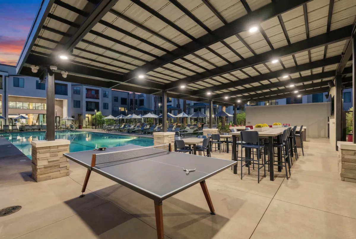 Outdoor amenity area features a pool, lounge chairs, ping pong table, and covered seating with tables and chairs.