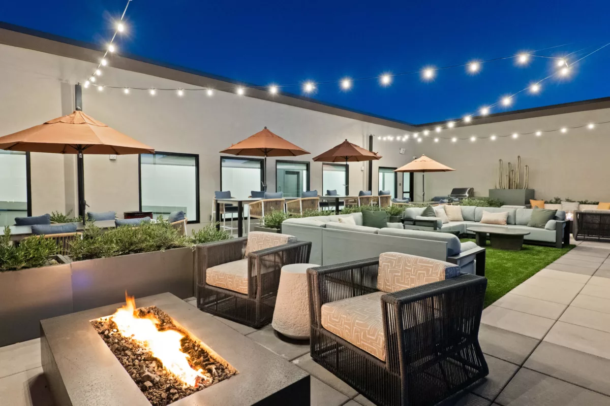 Outdoor rooftop lounge features a fire pit, seating areas, dining tables, and string lights.