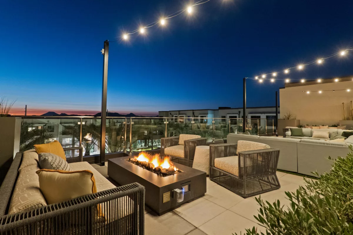 Rooftop lounge features a fire pit, cushioned seating, string lights, and views of the mountains.