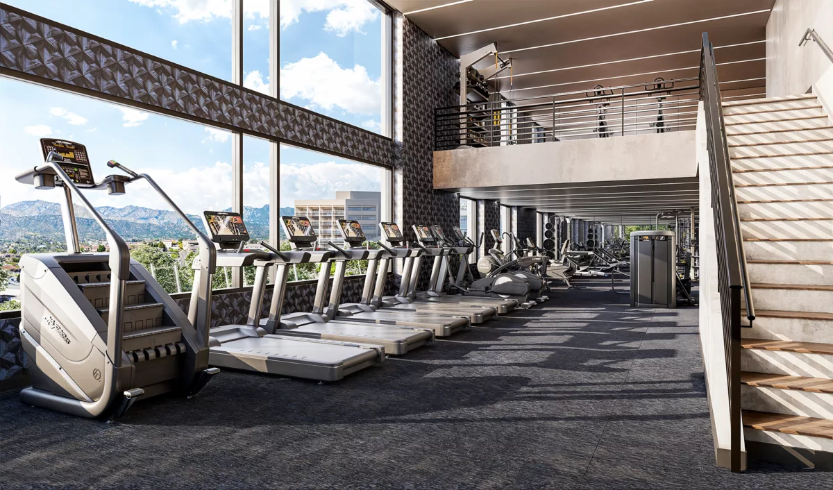 Modern gym with treadmills, weight machines, and floor-to-ceiling mountain views.