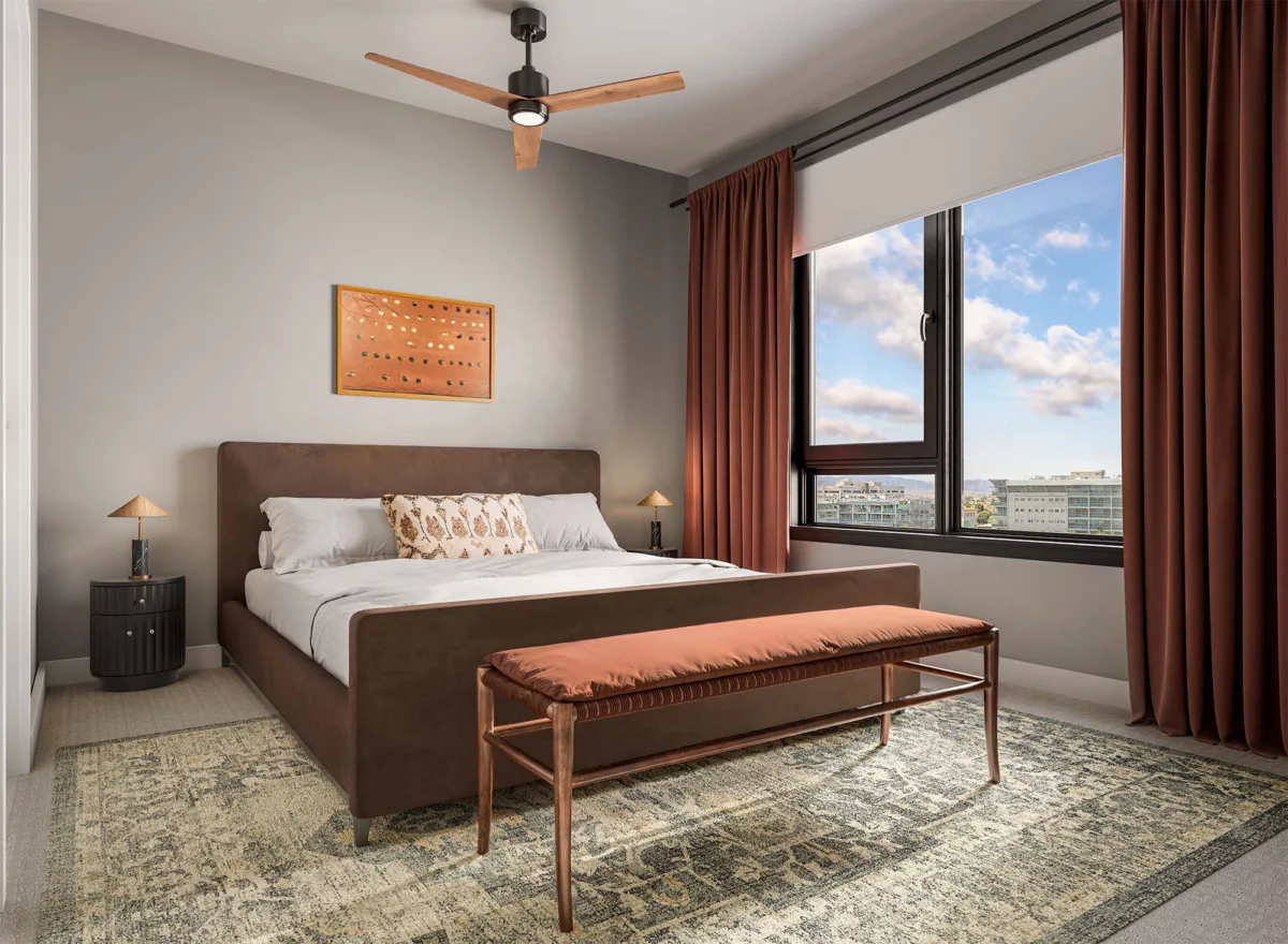Contemporary bedroom with upholstered bed, bench, and large window overlooking the city.