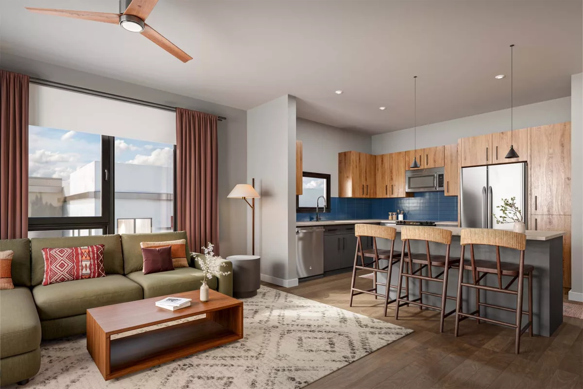 Open kitchen and living area with wood cabinetry, island seating, and large bright windows.