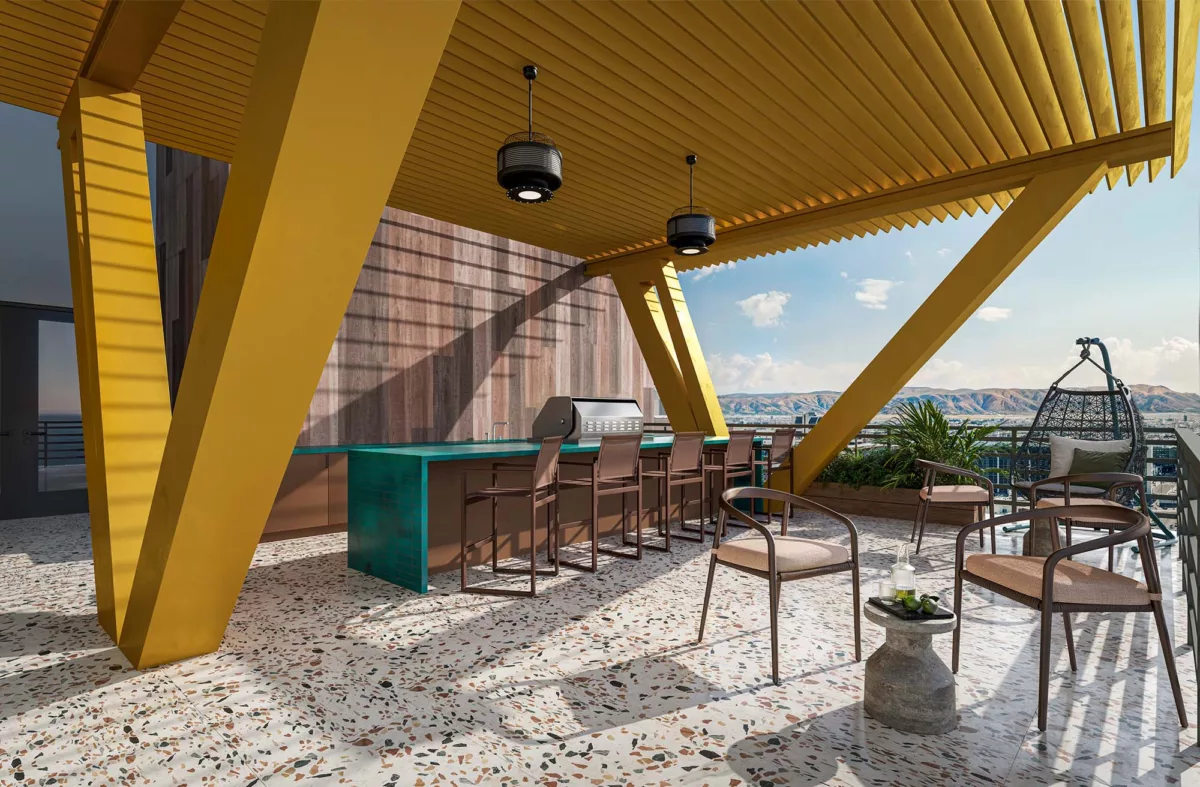 Outdoor sun deck with grill station, bar seating, and mountain views under yellow canopy.