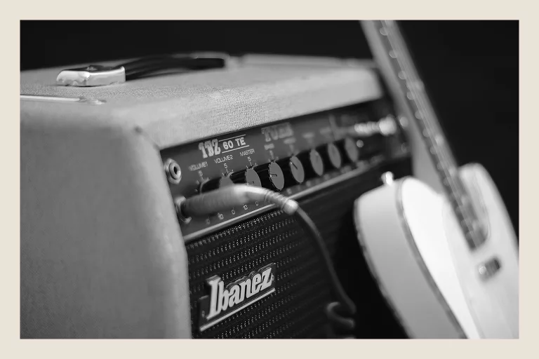 Black and white close-up of Ibanez guitar amp with white electric guitar