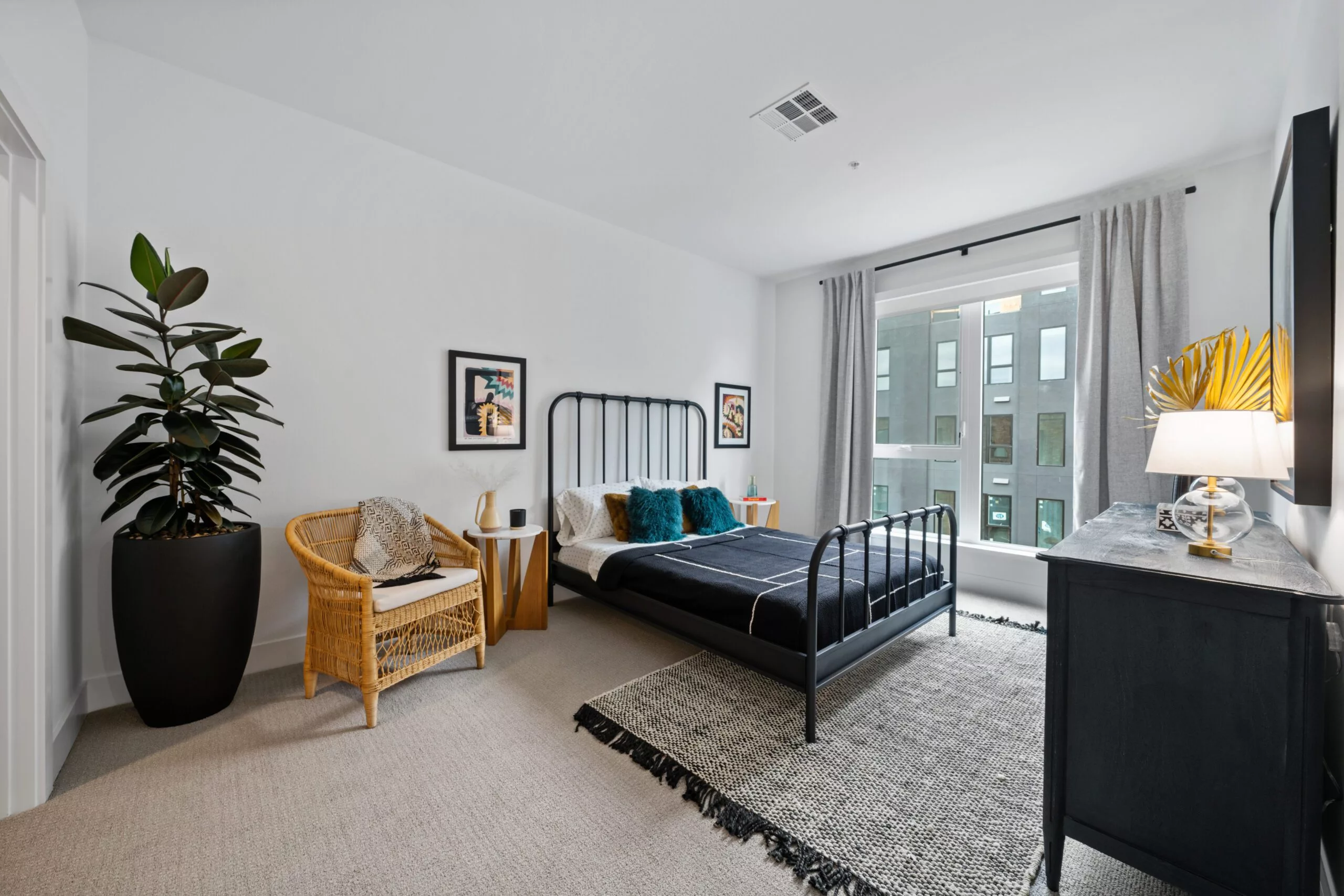 Cozy bedroom with large window, patterned rug, and neutral-toned decor accents.