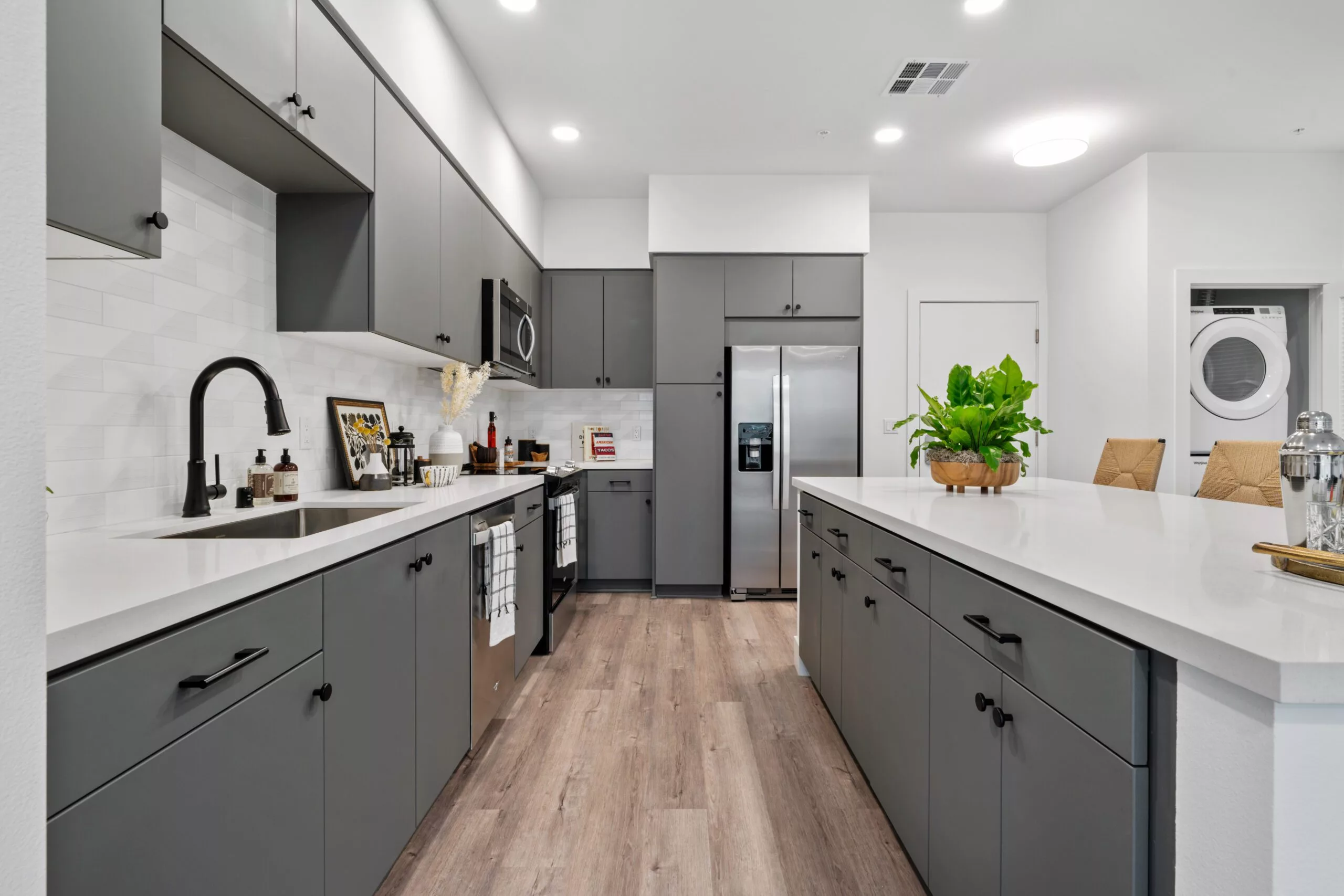Contemporary kitchen with gray cabinetry, white countertops, and stainless steel appliances.