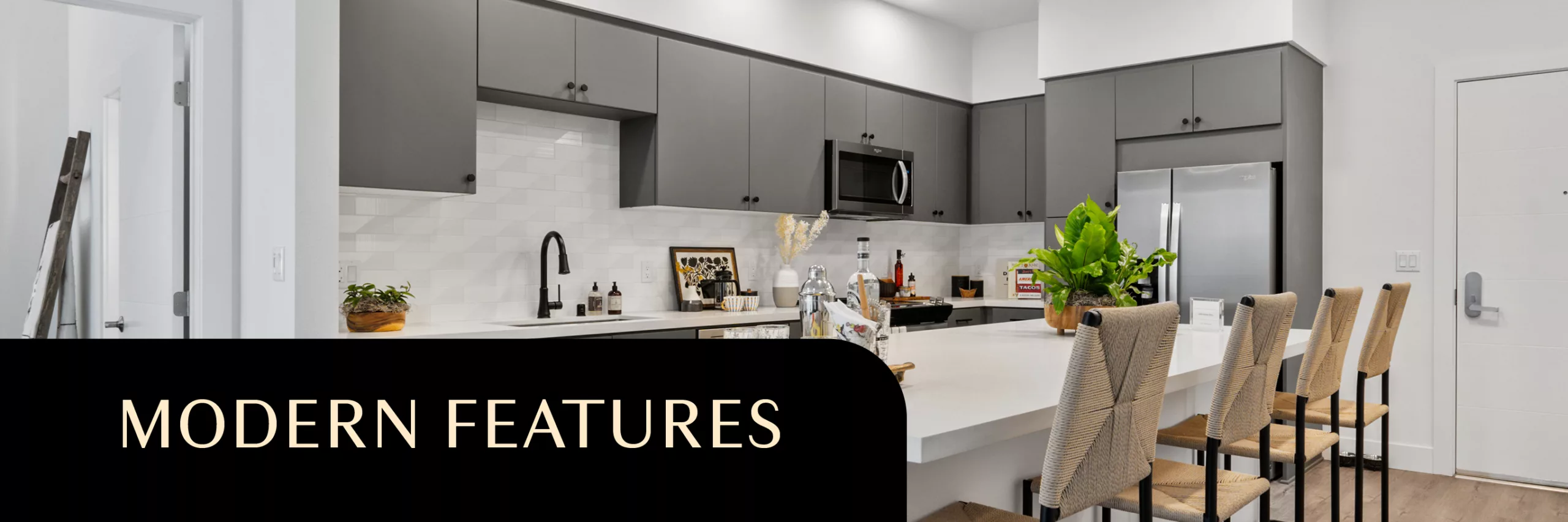 Sleek modern kitchen with gray cabinets, white island, and woven-back bar stools.