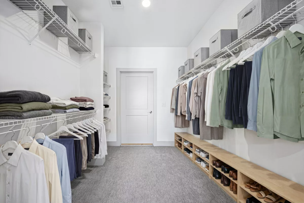 Large closet with wire shelving, hanging clothes, and a built-in wooden shoe rack.