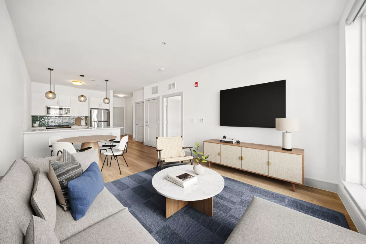 Open-concept living room with a kitchen, dining area, and hardwood floors.