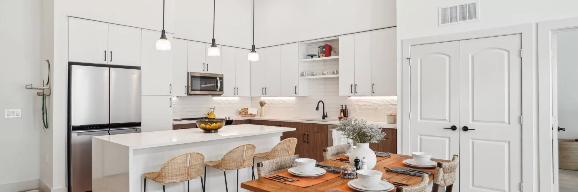 Kitchen with white and brown cabinets, center island, and hanging pendant lights