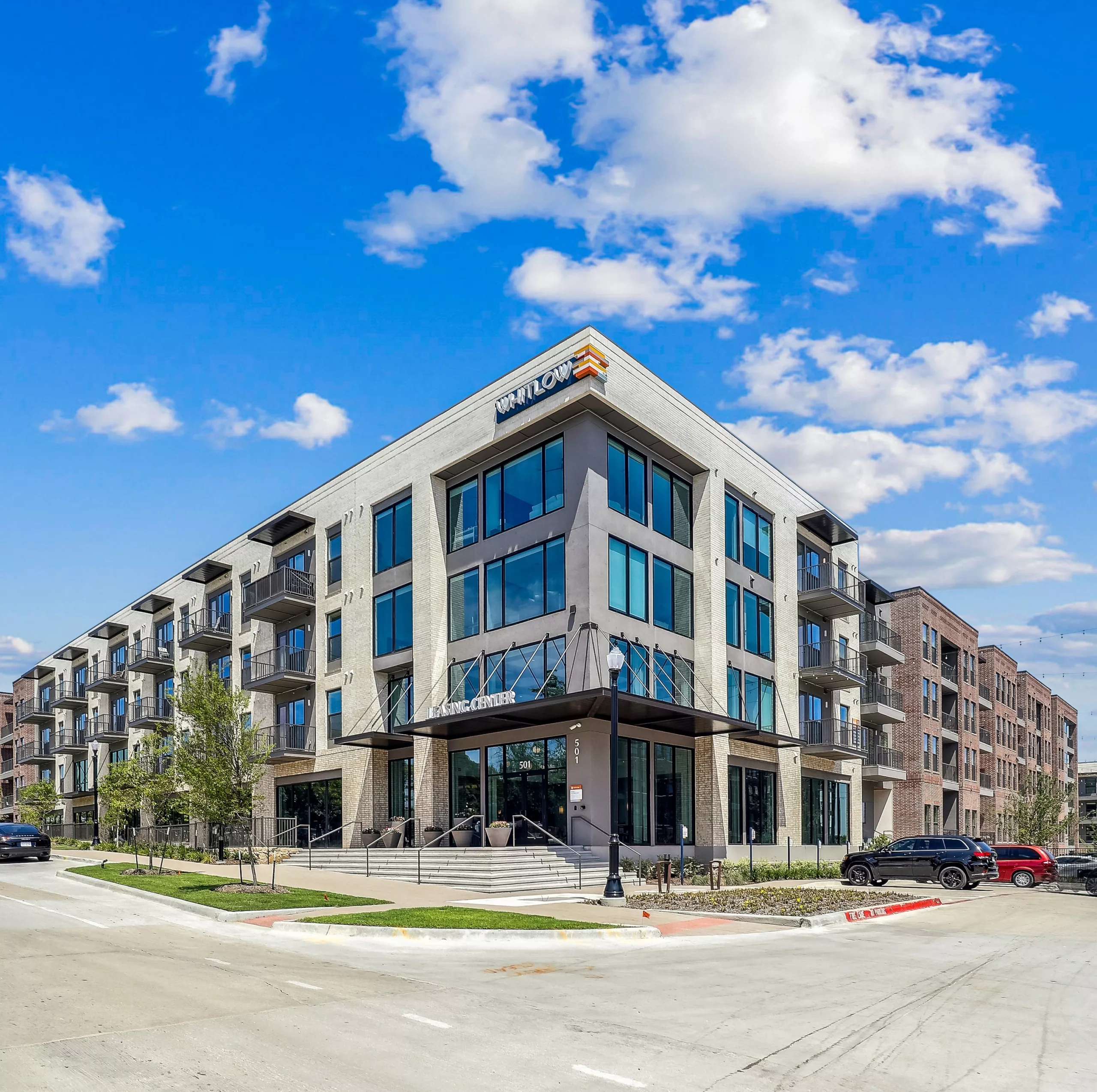 Modern residential building entrance with large steps, leading to a lobby.