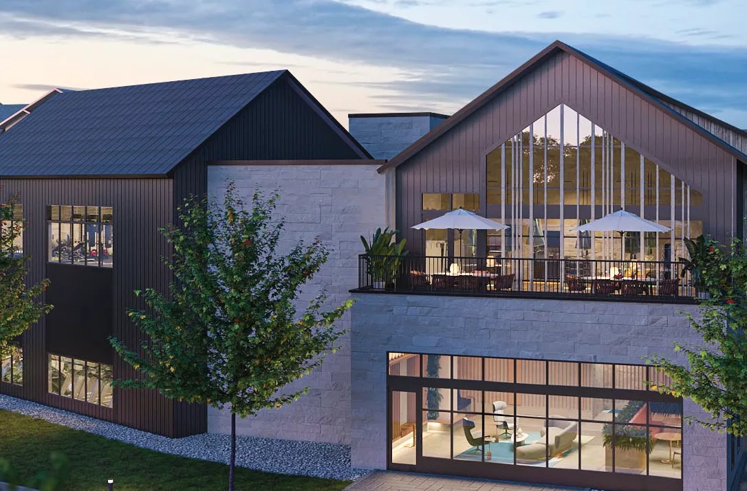 Evening exterior of a clubhouse with patio seating and large windows.