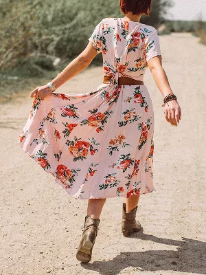 Person in pink floral dress walking on dirt path outdoors