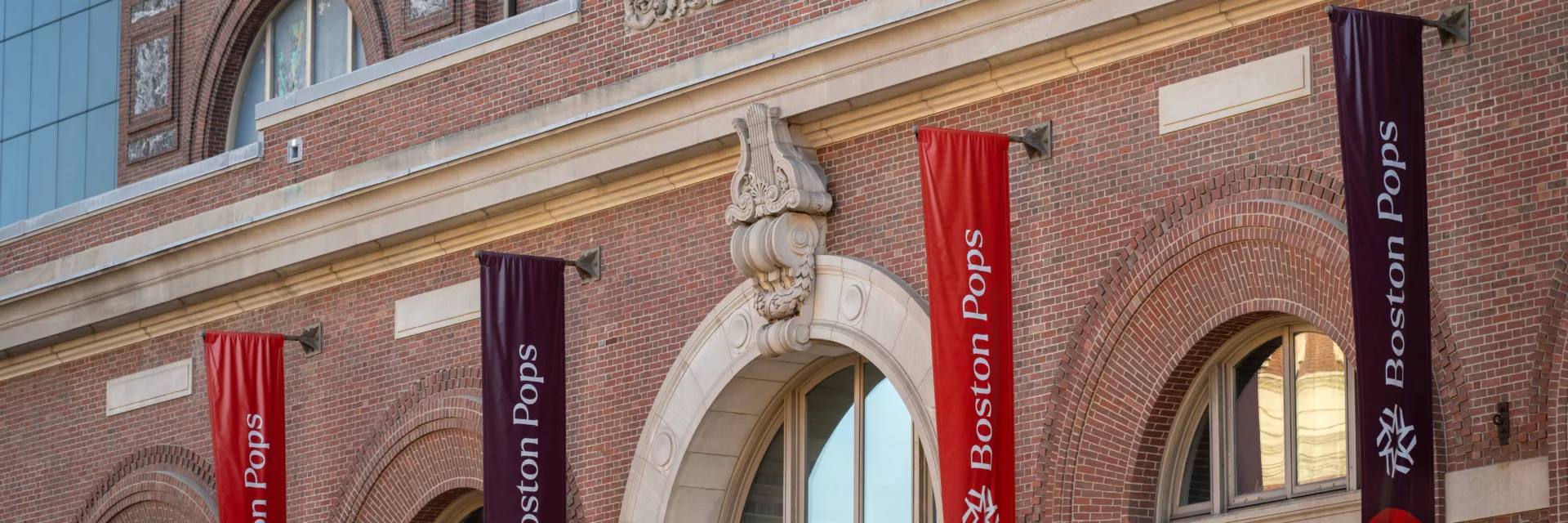 Historic brick theater facade with arched windows and “Boston Pops” banners