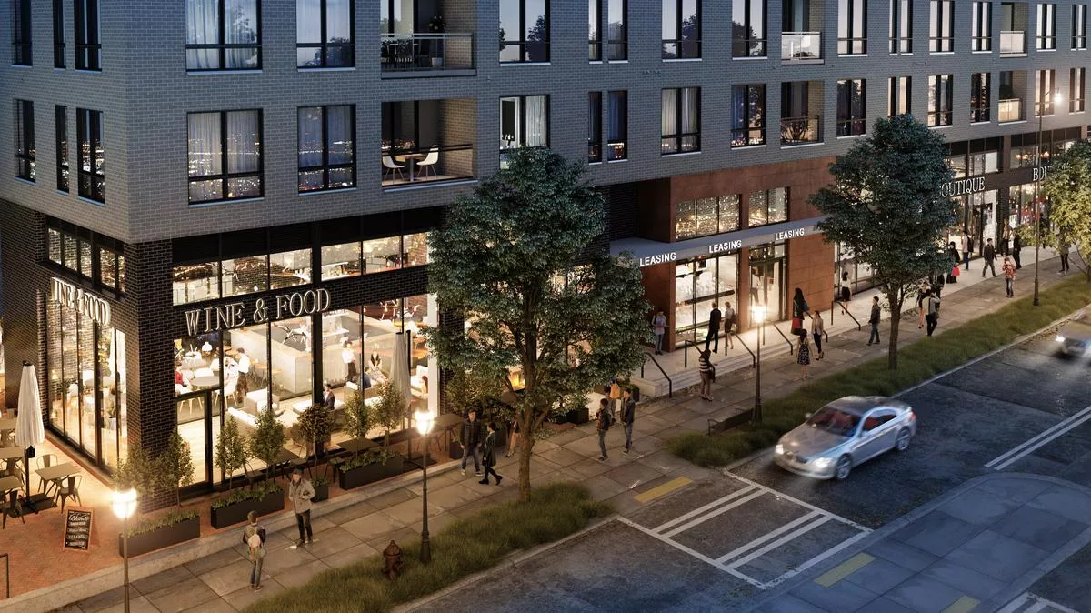 Street-level evening view of a modern apartment building with large retail windows labeled “WINE & FOOD,” busy with pedestrians and light street traffic.