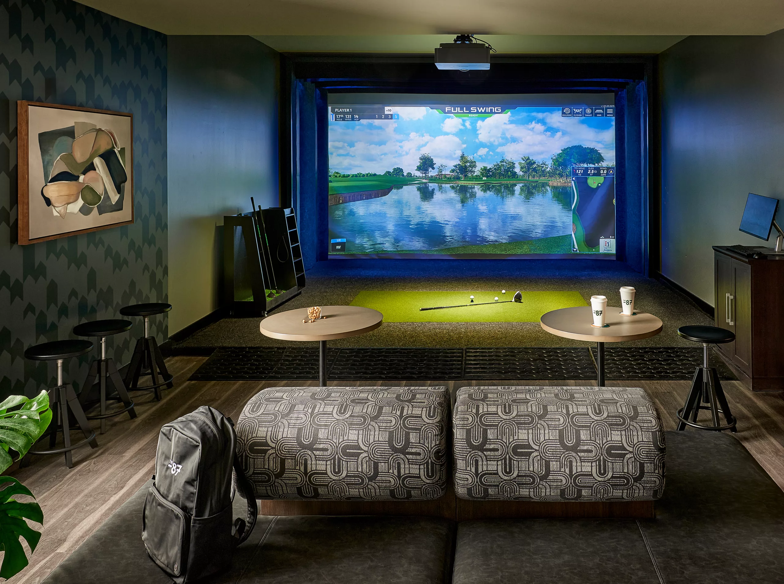 Golf simulator room with lounge seating and putting green