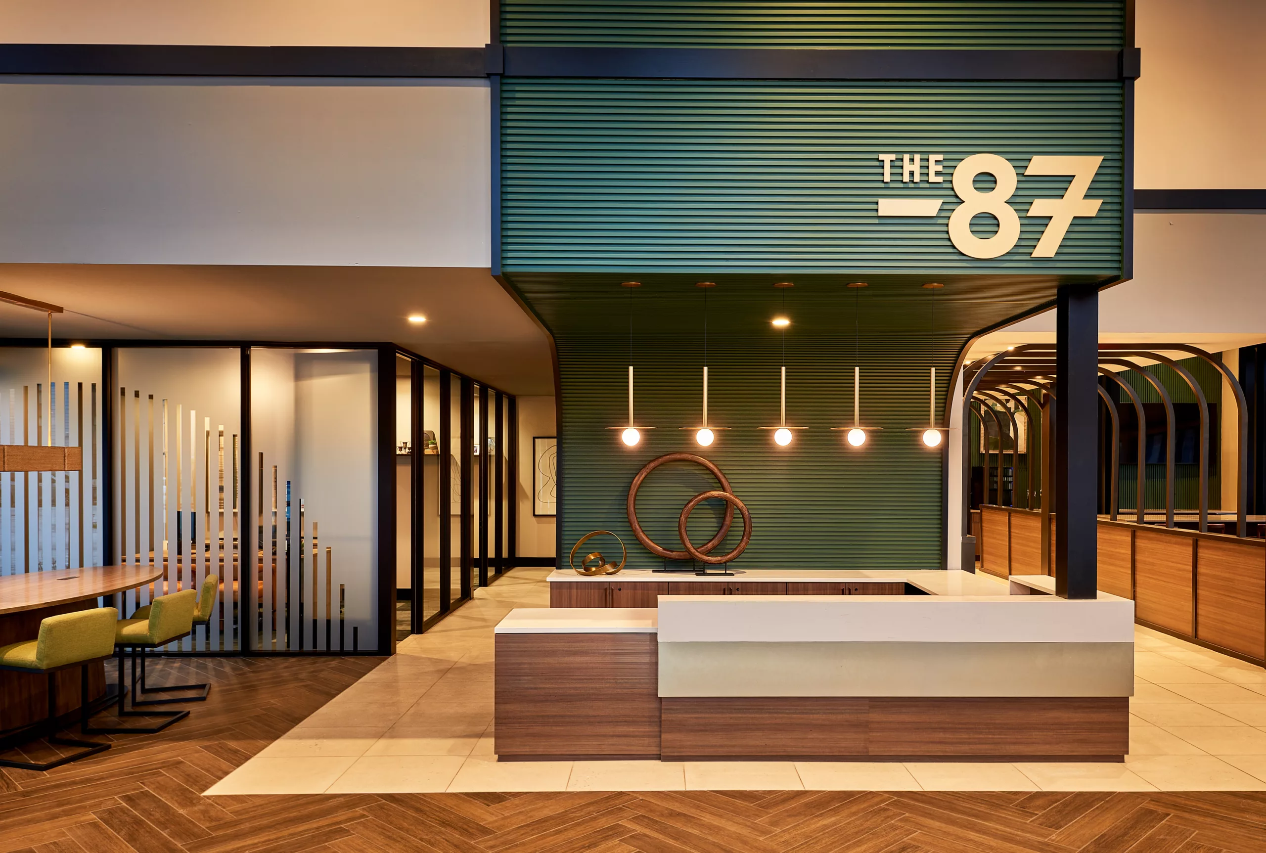 Reception desk under green accent wall with pendant lights