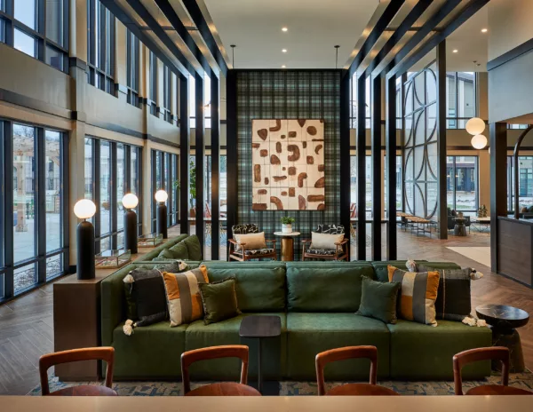 Double-height lobby with green sectional and patterned wall
