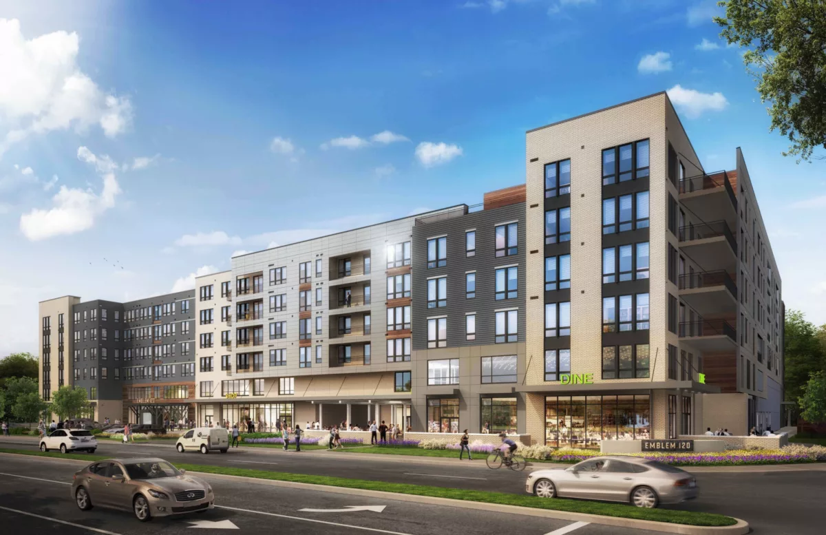 Mixed-use urban apartment building with a modern facade in neutral tones, retail shops at the ground level, and a vibrant street scene with cars and pedestrians.