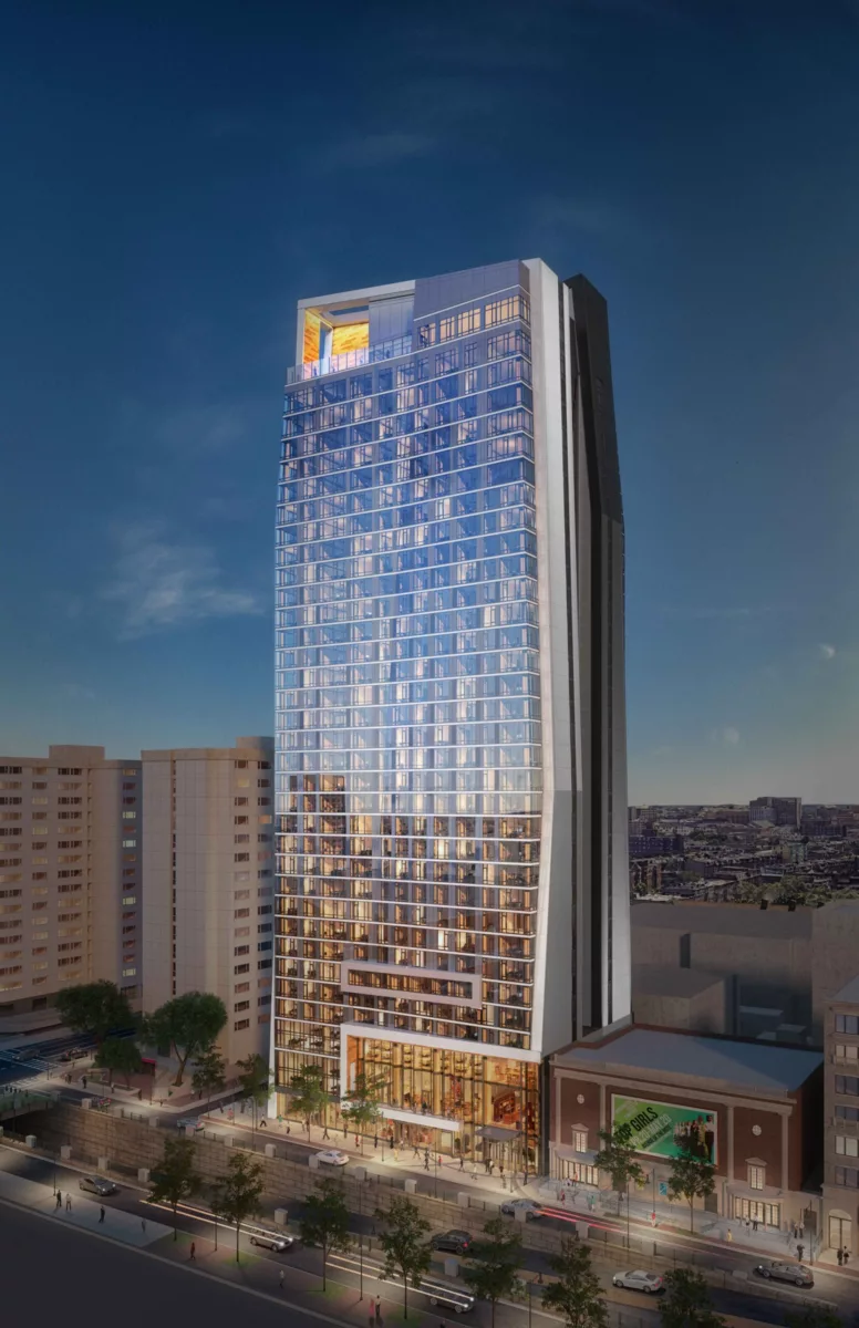 Sleek glass high-rise with angled architecture and glowing rooftop, set against a twilight sky