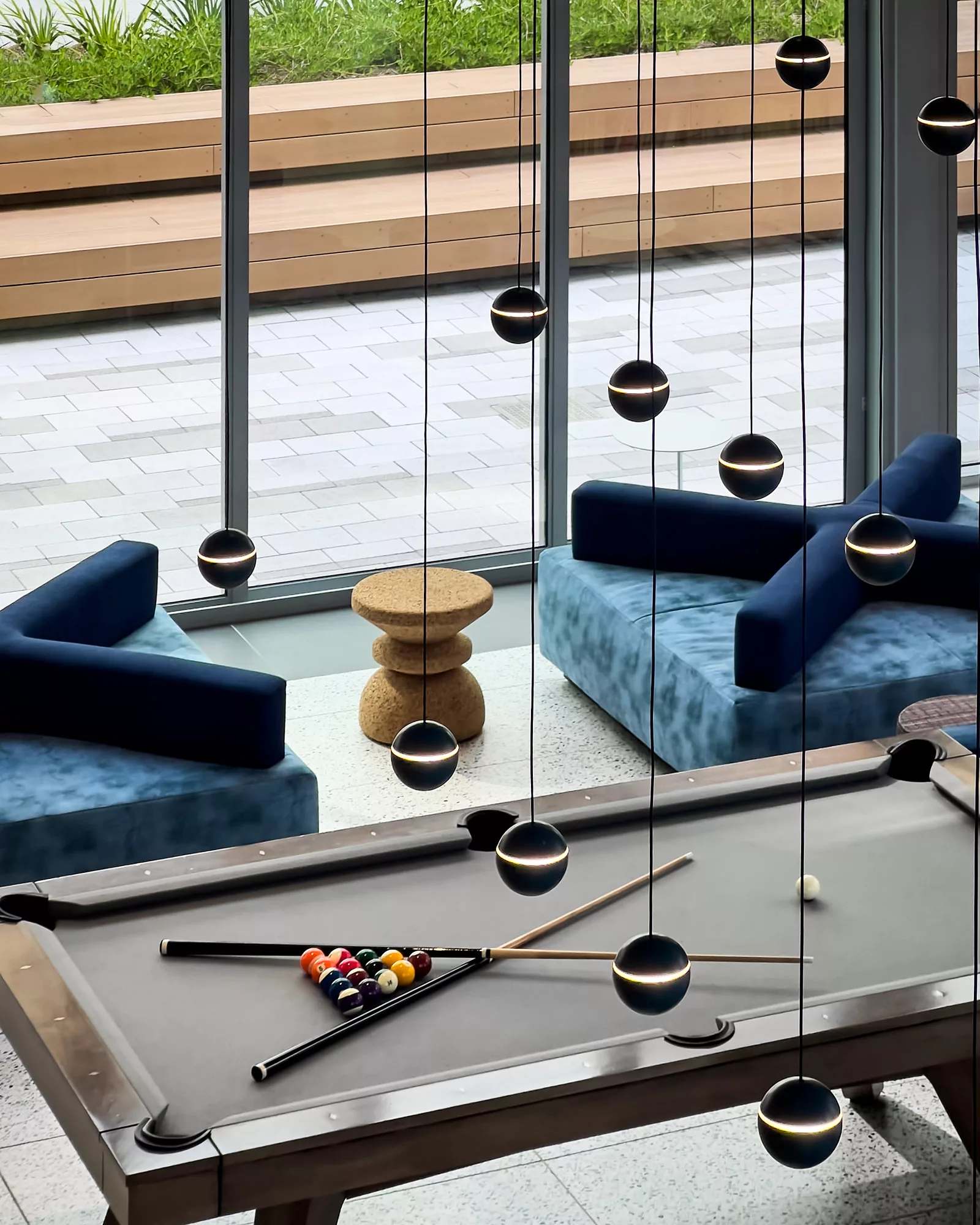 Modern lounge with pool table, blue sofas, and globe pendant lights
