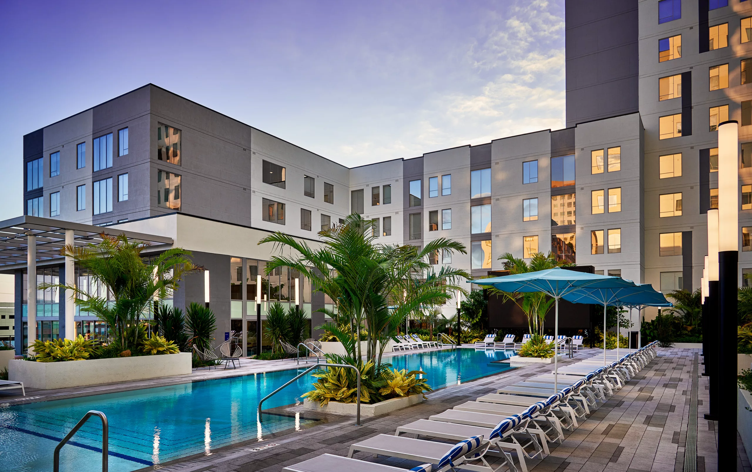 Pool courtyard with lounge chairs, palm trees, and modern architecture