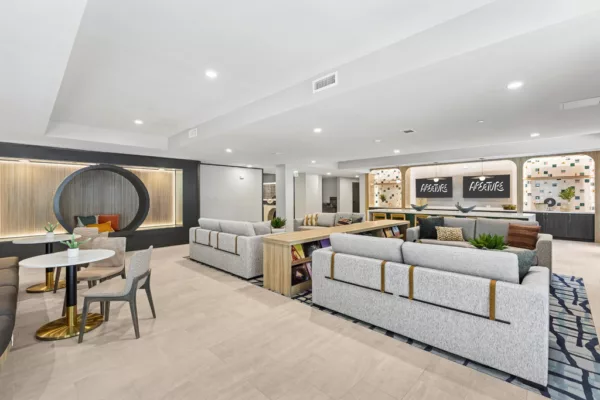 Lounge area with multiple couches, tables, and a large kitchen