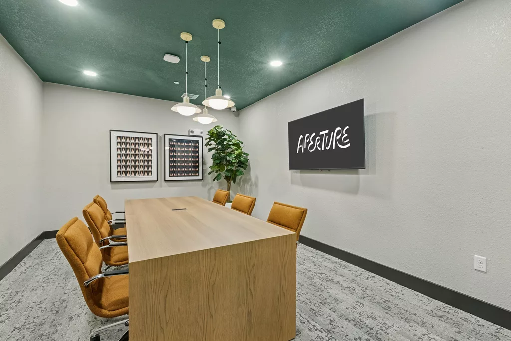 Conference room with long table, chairs, and wall-mounted TV