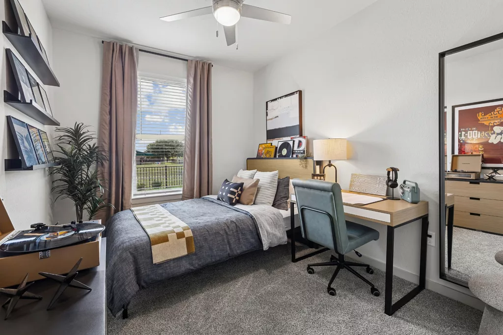 Bedroom with bed, record decor, desk, and window view