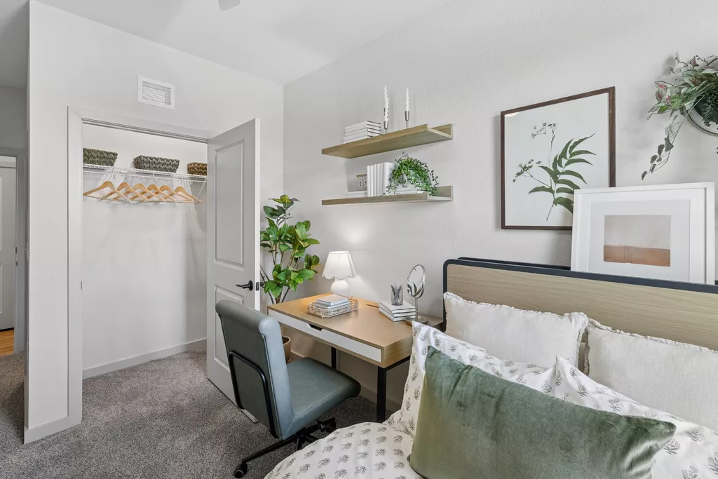 Bedroom with bed, open closet, desk, and wall shelves