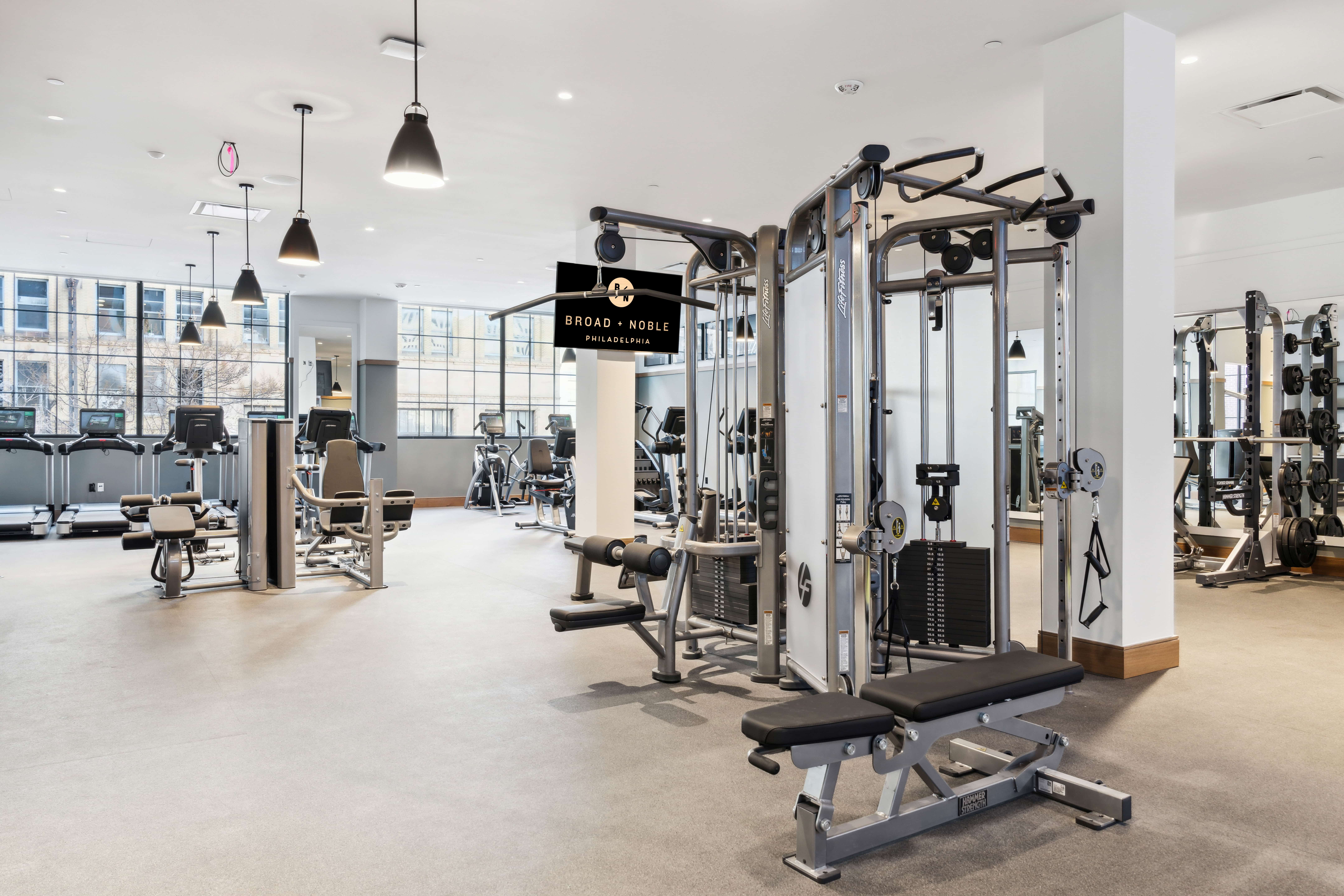 Spacious gym with machines, weights, and large windows
