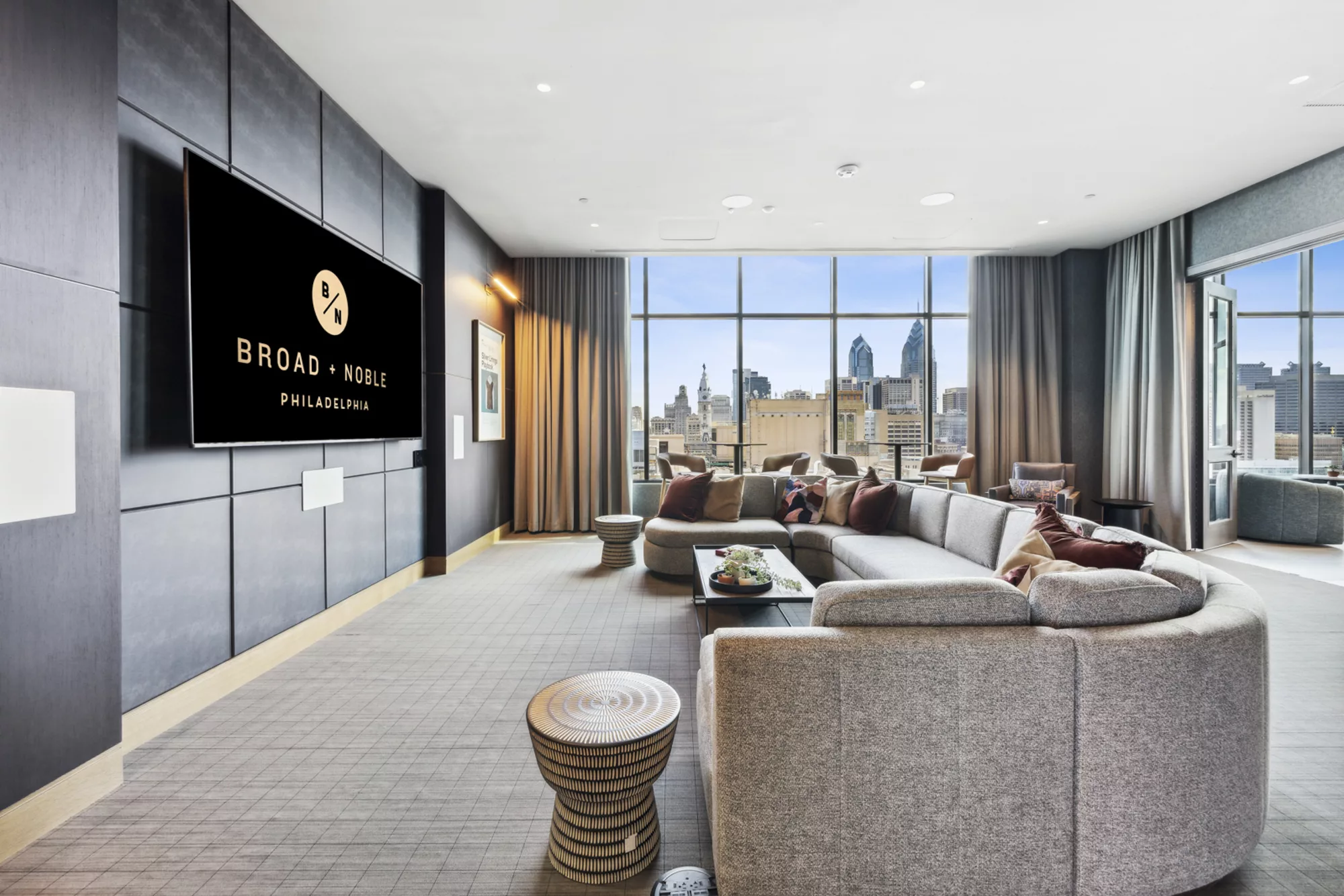 Media lounge with large TV, curved sofa, and city view