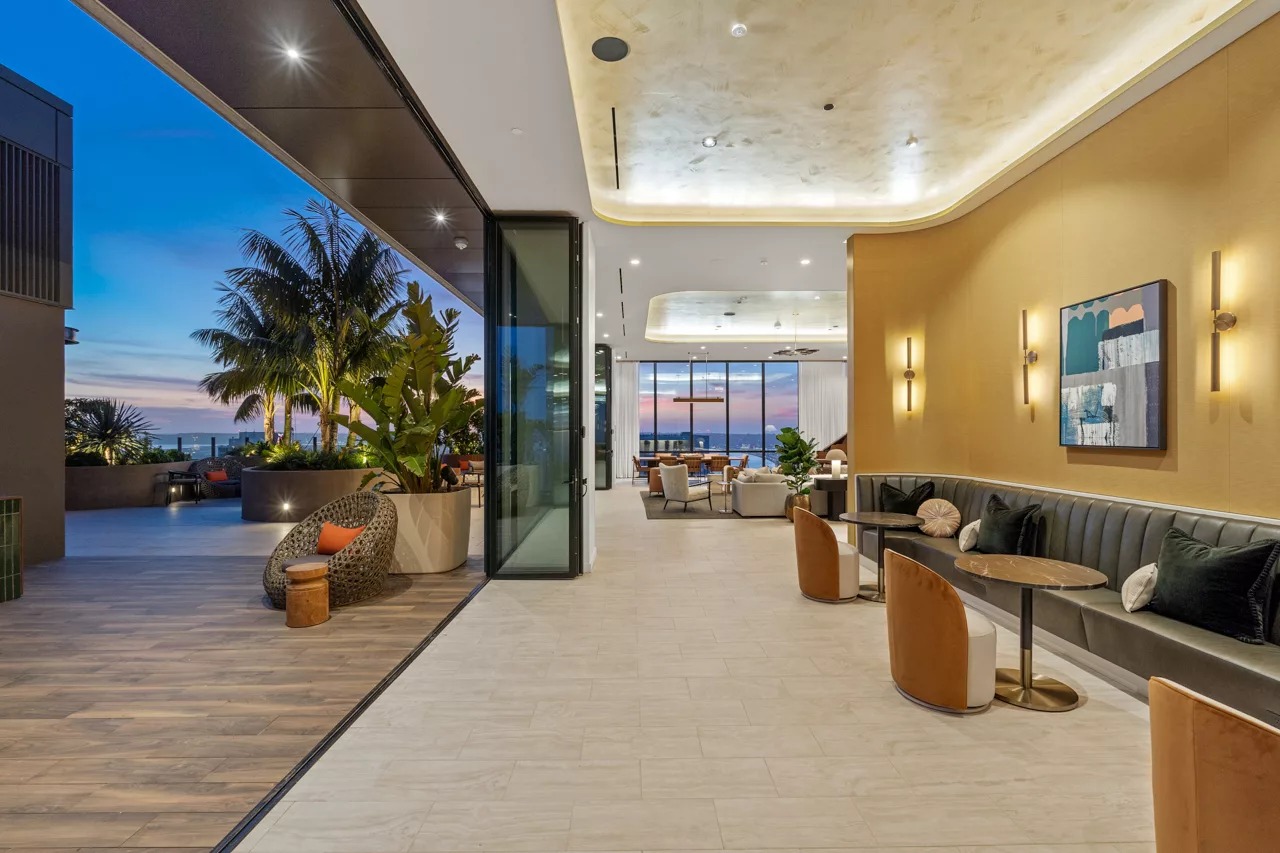 Indoor-outdoor lounge with plants and ocean view at dusk