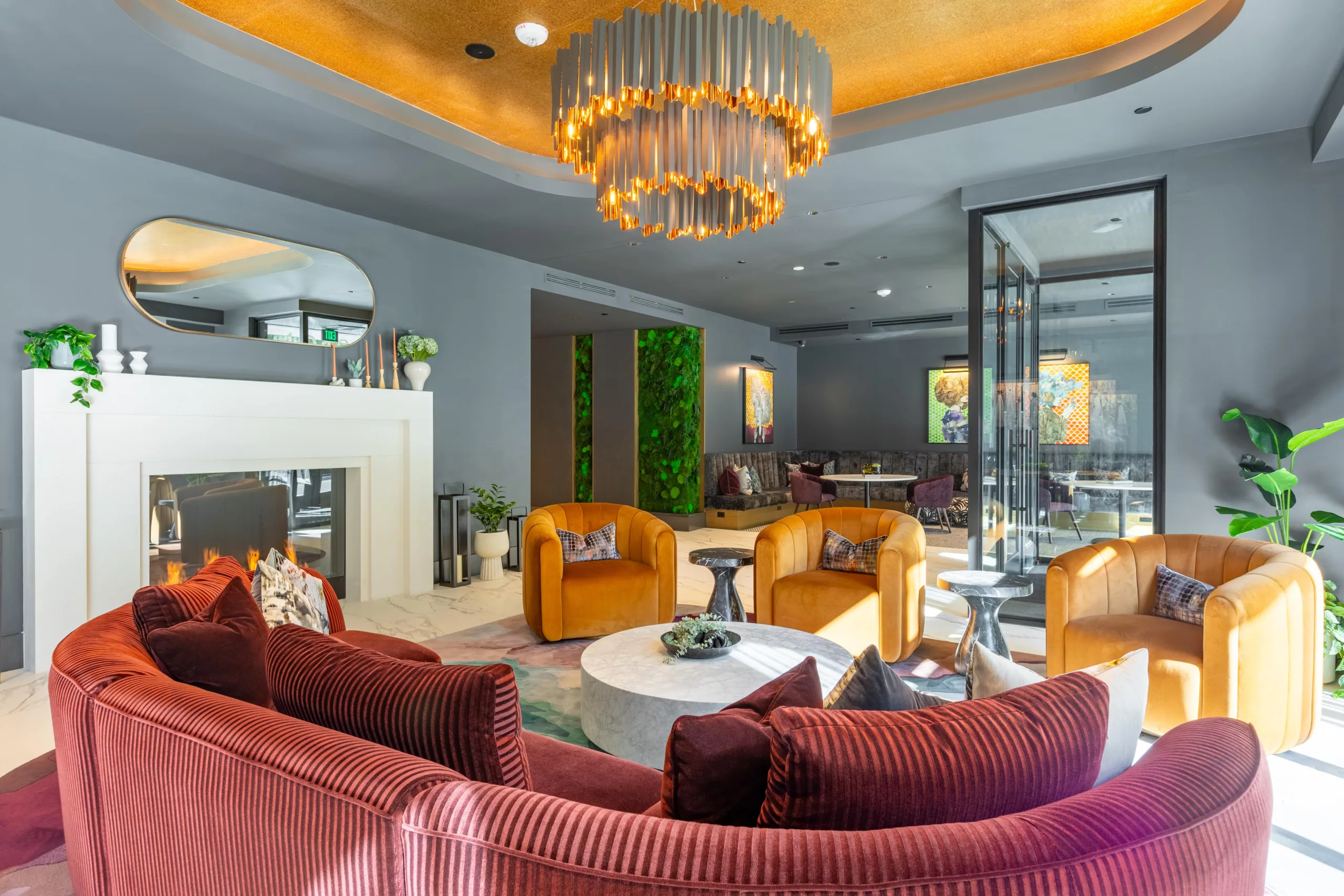 Stylish lounge with curved seating, gold ceiling, and modern chandelier.