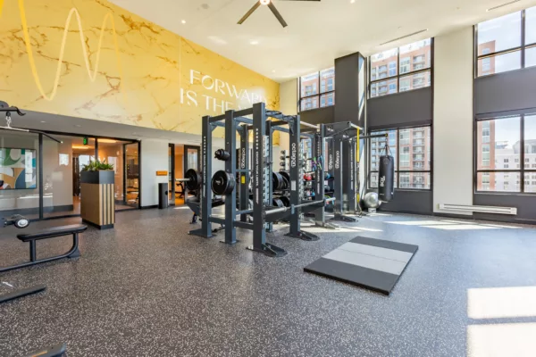 Spacious gym with weightlifting equipment and motivational wall text.