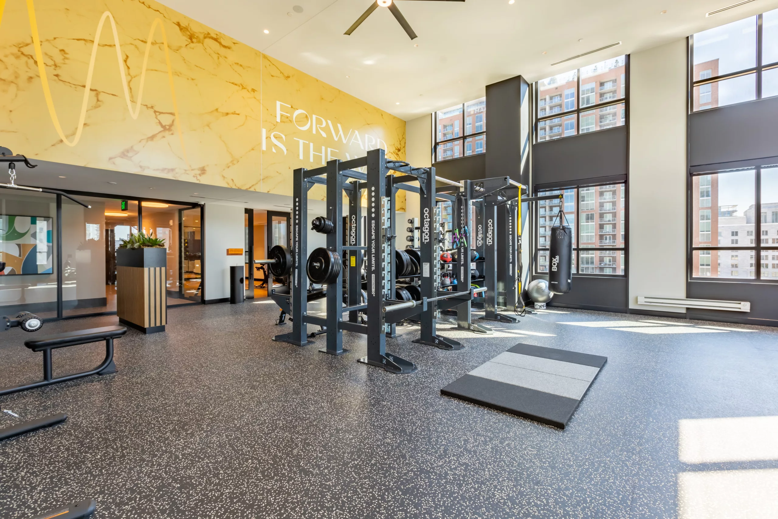 Spacious gym with weightlifting equipment and motivational wall text.