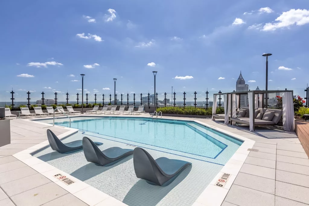 Rooftop pool with lounge chairs, cabanas, and city skyline views.
