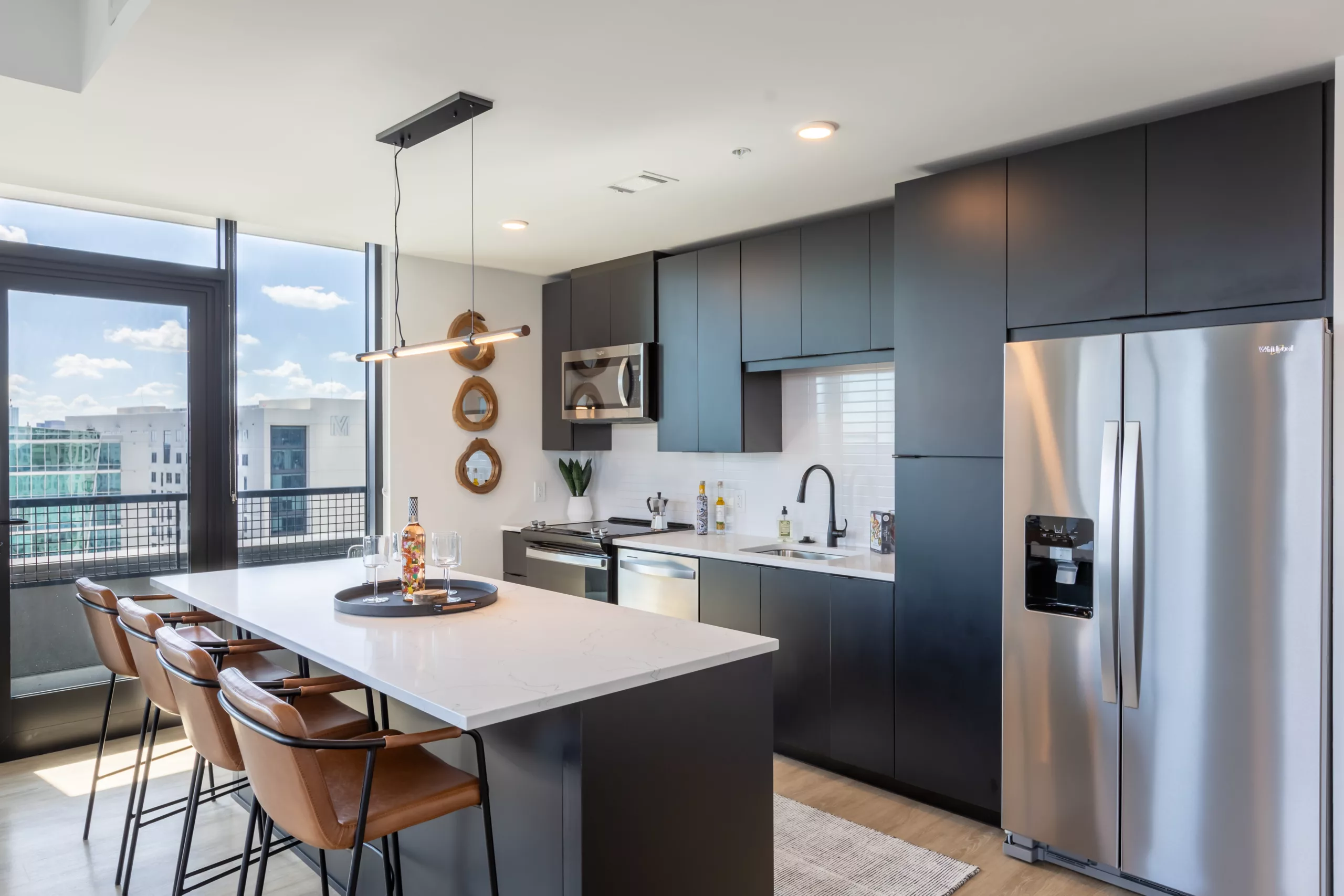Modern kitchen with dark cabinets, stainless appliances, and island seating.