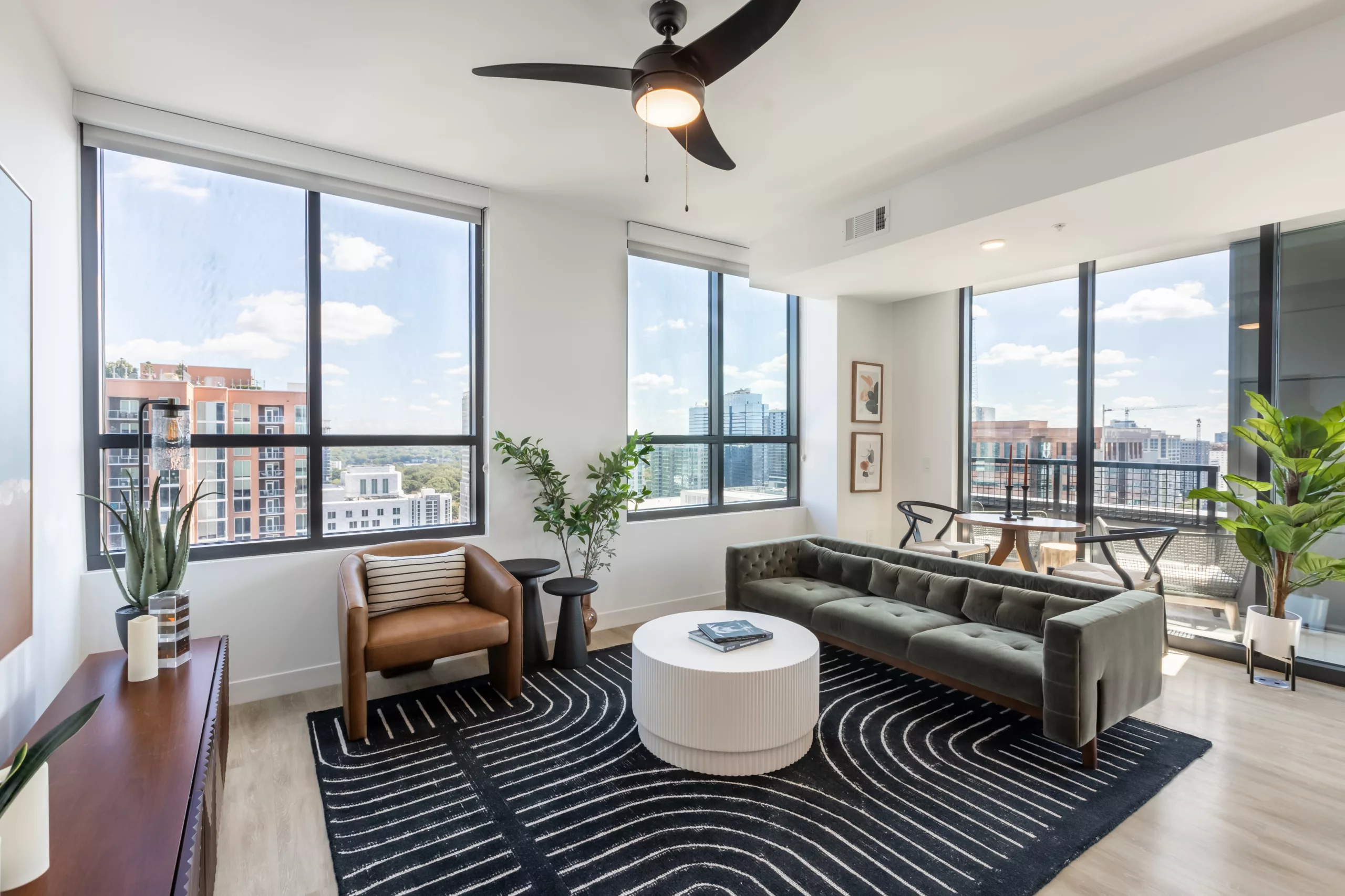 Bright living room with large windows, black sofa, and patterned rug.