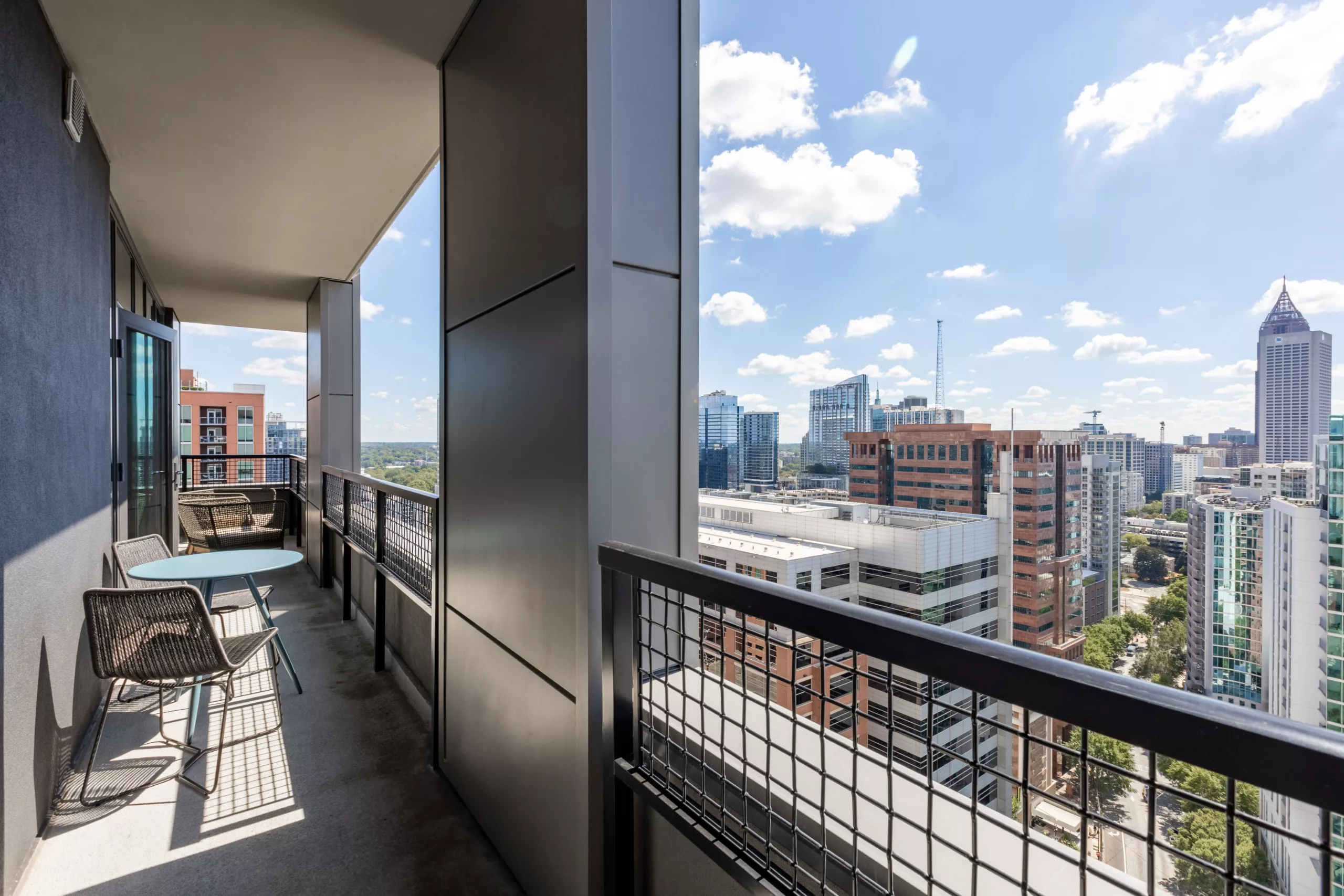 Balcony with patio furniture overlooking a city skyline under blue sky.