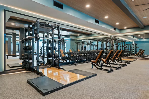 Fitness center with weight racks, benches, and mirrored walls.