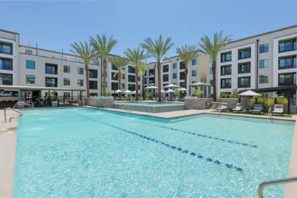 Outdoor pool area with fountains, palm trees, and lounge chairs.