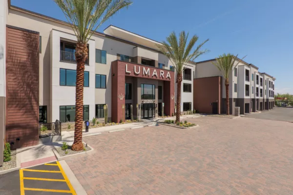 Modern apartment building with "Lumara" sign and palm trees at the entrance.