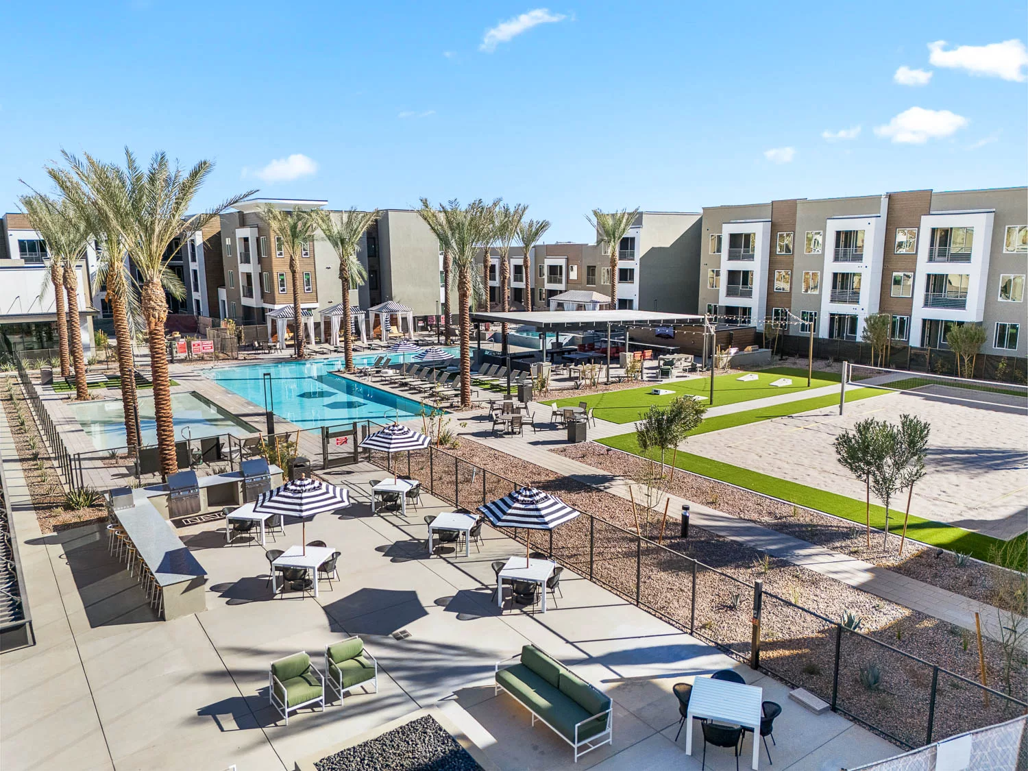 Outdoor pool area with lounge seating and sand volleyball court.